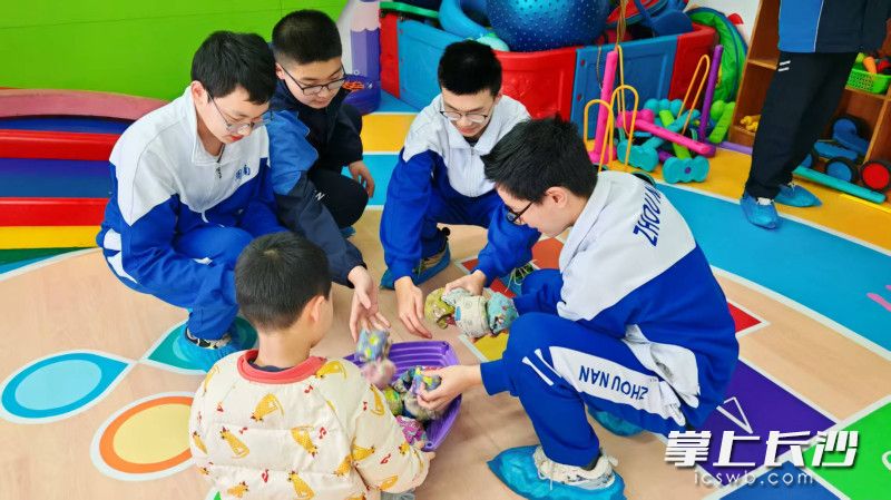 “周小南”们耐心陪伴“星星的孩子”玩游戏。