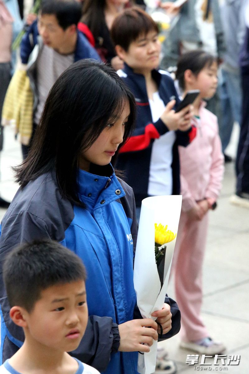 一名中学生手持菊花献英烈。