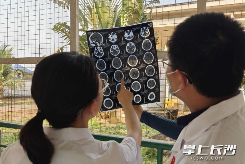 放射科陈娟医生和神经外科李征医生在室外走廊利用日光透视CT胶片。均为受访者供图