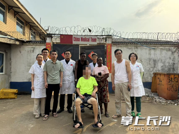 全体参与救治人员与坐在轮椅上的老张，在医院门口合影。