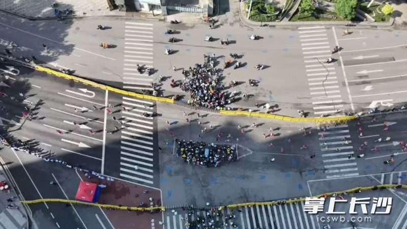 民警利用参赛选手奔跑出现的短暂断流间隙，像钟摆一样交替切换管控方向，快速而有序地组织市民分批横穿赛道，实现“动态放行、安全通过”。视频截图