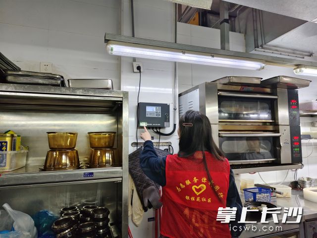 社区网格员查看餐饮门店燃气报警器。