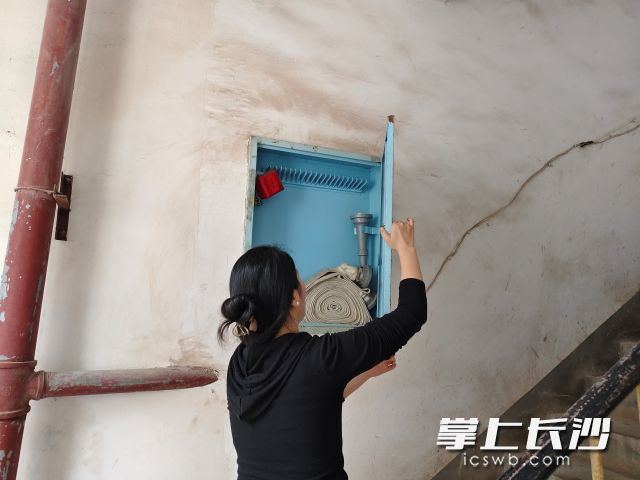 社区网格员正在查看网格楼道消防器材。
