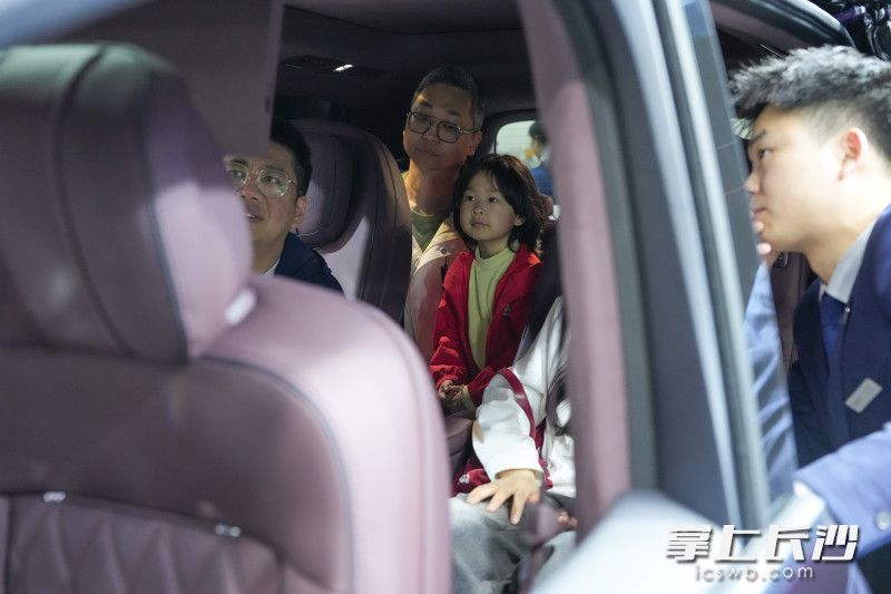 家长带着小孩一起看车，体验新能源车的高配置。