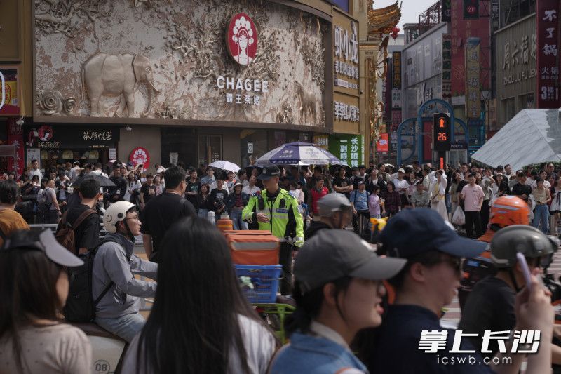 黄兴路步行街北路口，人们在交警的指挥下有序过马路。
