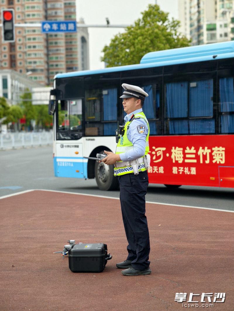 交警在路口操纵无人机，巡查道路通行情况。