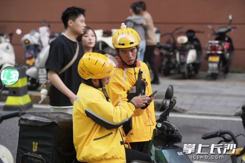 面对复杂的路口，年轻的外卖员向经验丰富的外卖员请教路线。