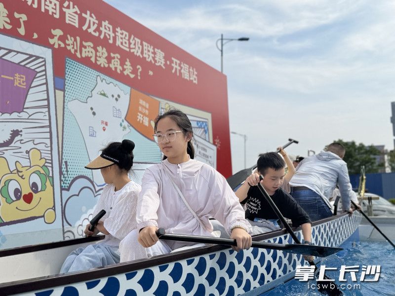 赛场下游客市民逛龙舟市集，划“陆上龙舟”不亦乐乎。