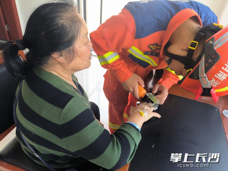 消防员在为老人取戒指。