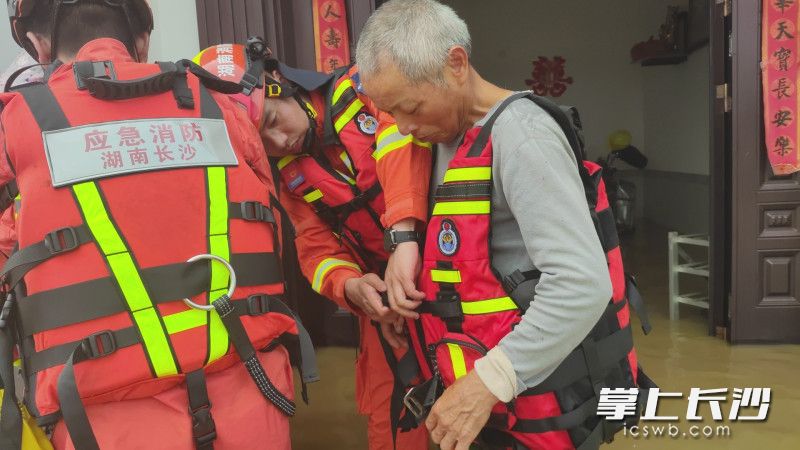 帮助受灾群众穿上救生衣。 帮助受灾群众穿上救生衣。