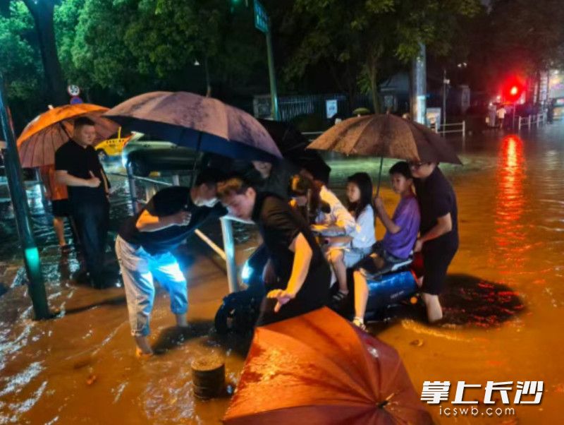 长沙县星沙街道、社区干部和路过的热心群众伸出援手，合力帮助受困母女脱离积水区域。长沙县星沙街道供图