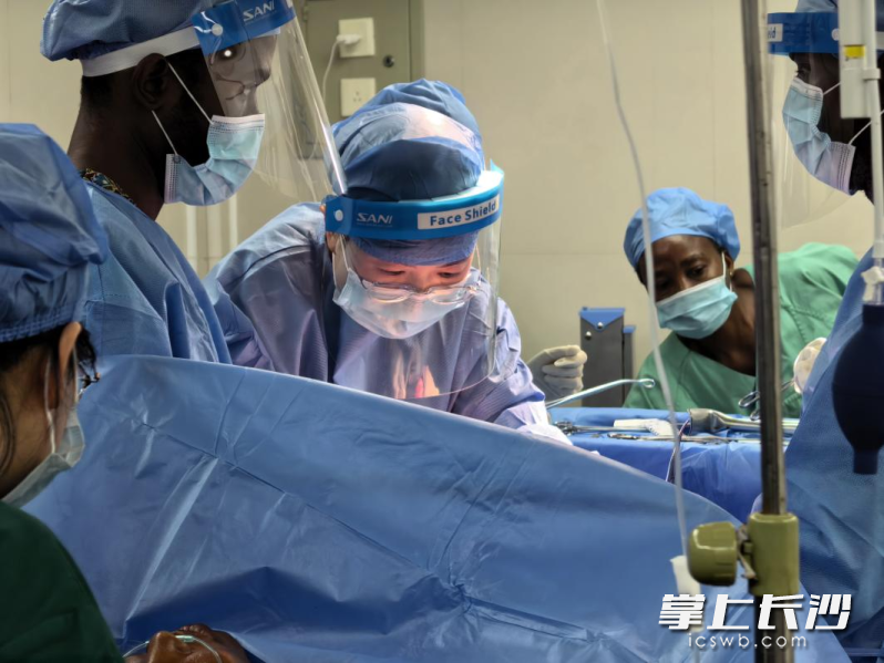 手术台上，妇科专家宋玉莹医生（中）正俯身专注操作，眼神透过面罩显得格外坚毅。身旁的塞方医护人员全神贯注地围拢在手术台旁，目光紧紧跟随中国专家的每一处刀落。作为当地首例高难度标准术式，这也是一次毫无保留的现场教学。受访者供图