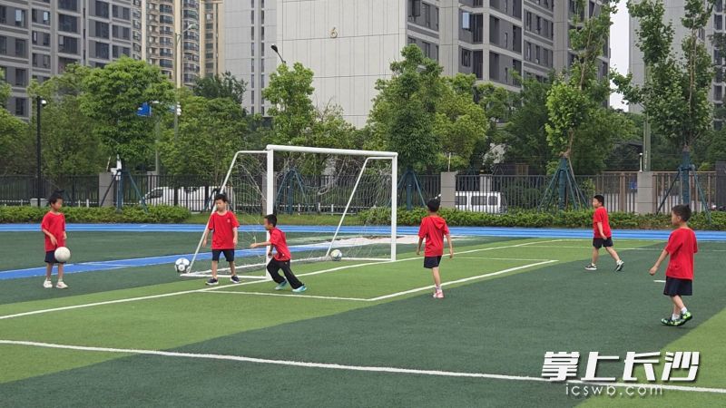 学生们到校放下书包后奔向操场踢球。