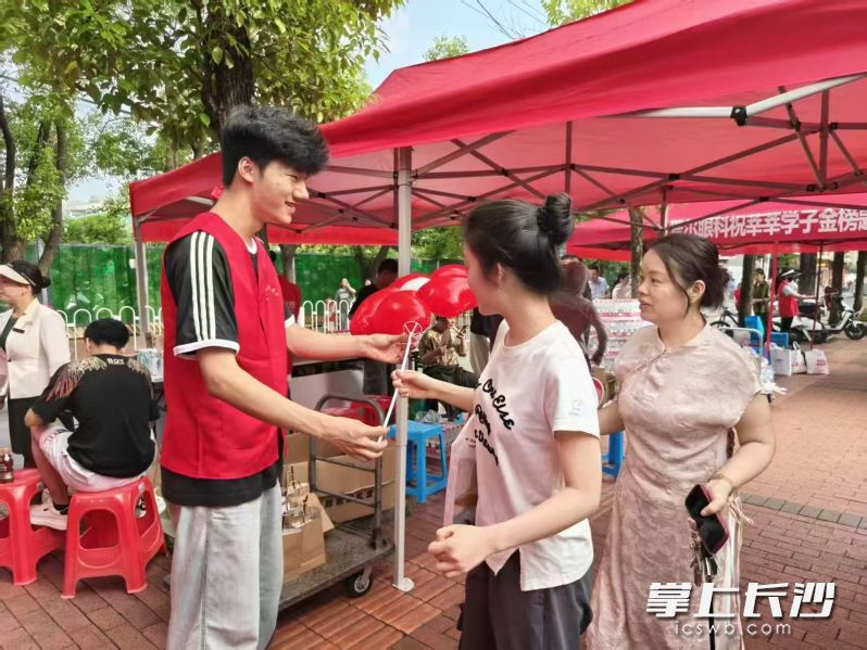 6月7日，在南雅中学考点外，来自湖南农业大学与东山街道的志愿者一起，搭建爱心加油站，开展爱心送考活动，为考生和家长送上饮用水、应急药品与祝福气球。长沙晚报全媒体记者 陈焕明 通讯员 刘晶 摄影报道