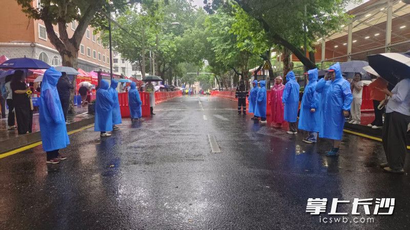 上午10时，雨势增大。清水塘街道社区志愿者引导接考家长有序站在指定区域，为考生下考留出通道。
