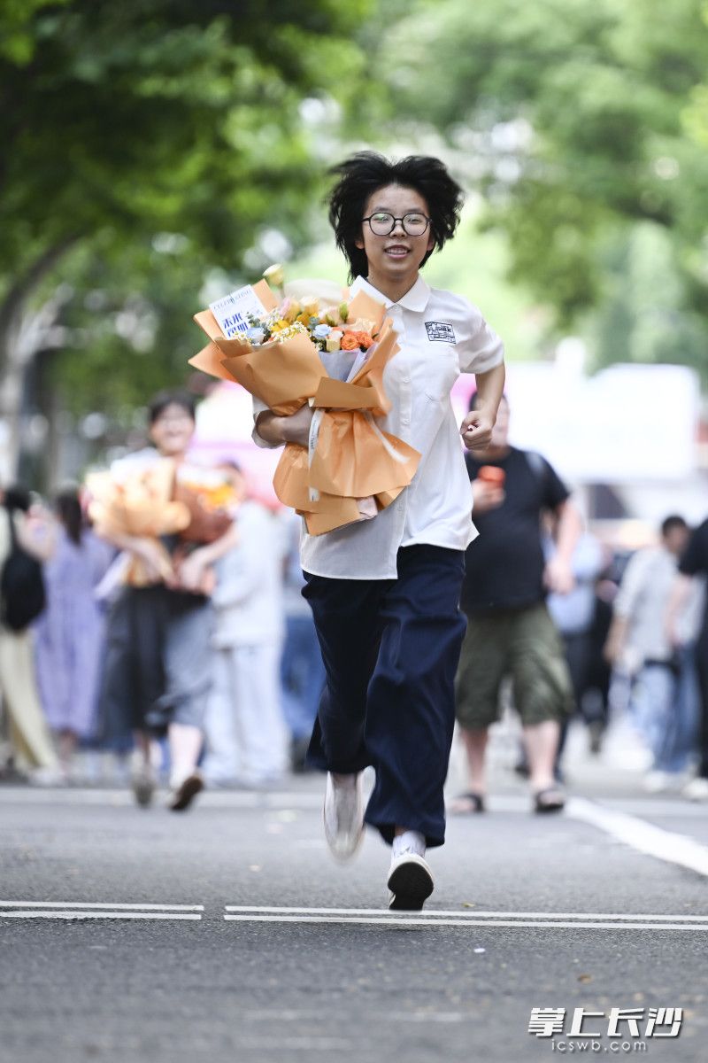 6月9日下午，结束了生物科目考试之后，长沙市一中考点，一位女生手拿鲜花跑过学校前的林荫道。
