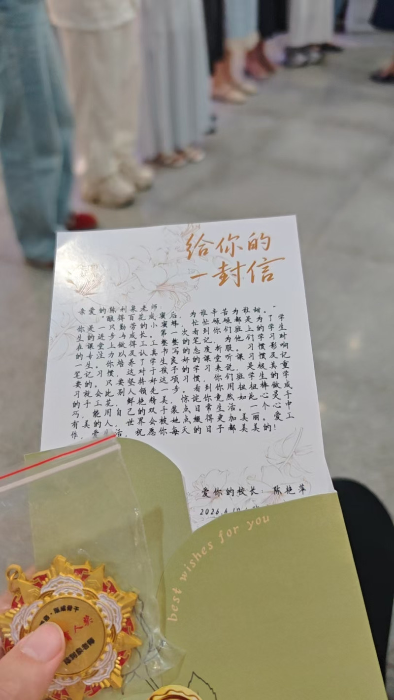 一位班主任展示她获得的荣誉奖章和校长写给她的信。