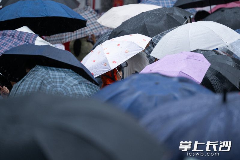 大雨中，家长撑伞等候下考的孩子。