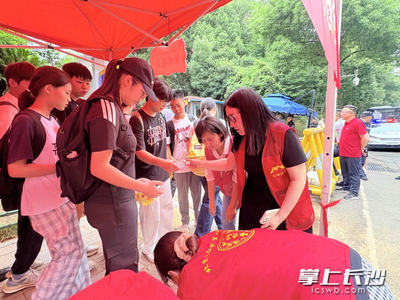 长郡月亮岛学校考点，志愿者给考生发放饮用水。