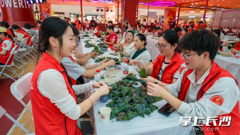 残友与雷锋志愿者两两搭档，折粽叶、填糯米、缠棉线……一个个棱角分明的粽子逐渐成形。 均为长沙晚报全媒体记者陈飞摄