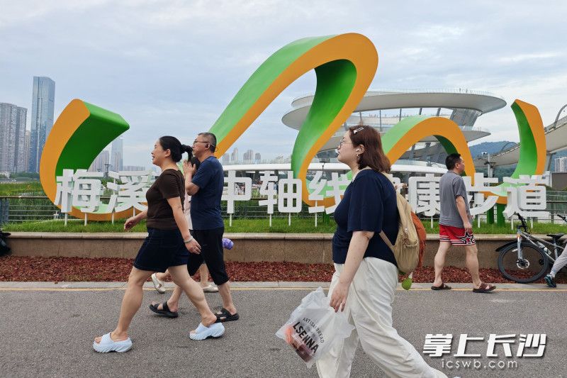 市民从梅溪湖中轴线健康步道前经过。