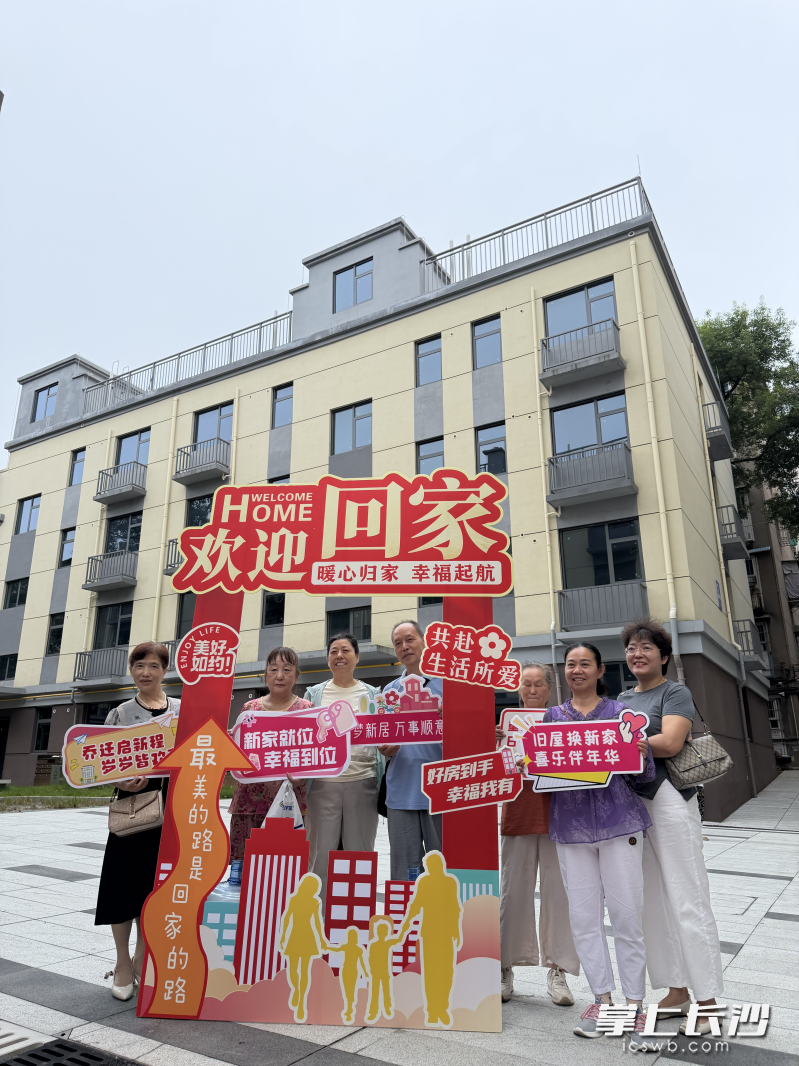 社区暖心设置了新居打卡点，领到钥匙的业主们在焕然一新的楼栋前合影。