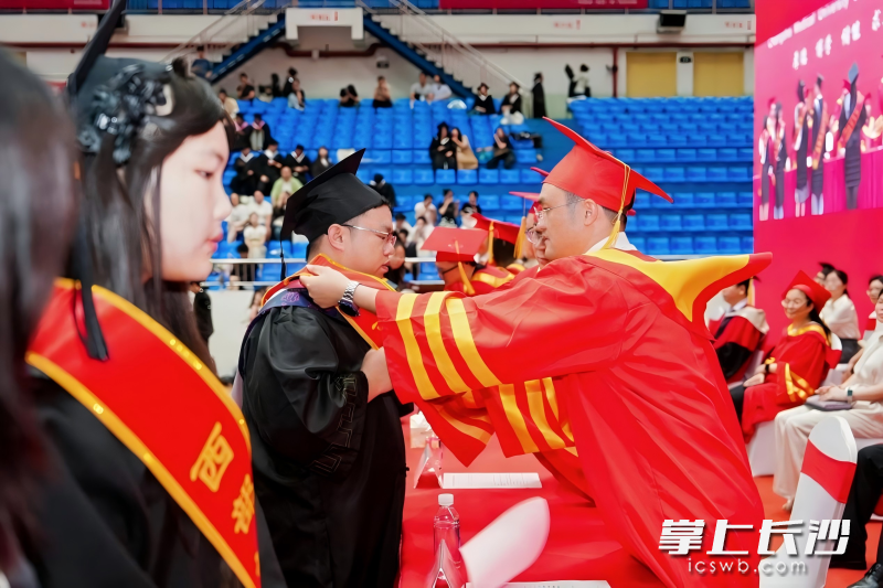 学校负责人为西部计划志愿者佩戴绶带，为他们送上祝福。