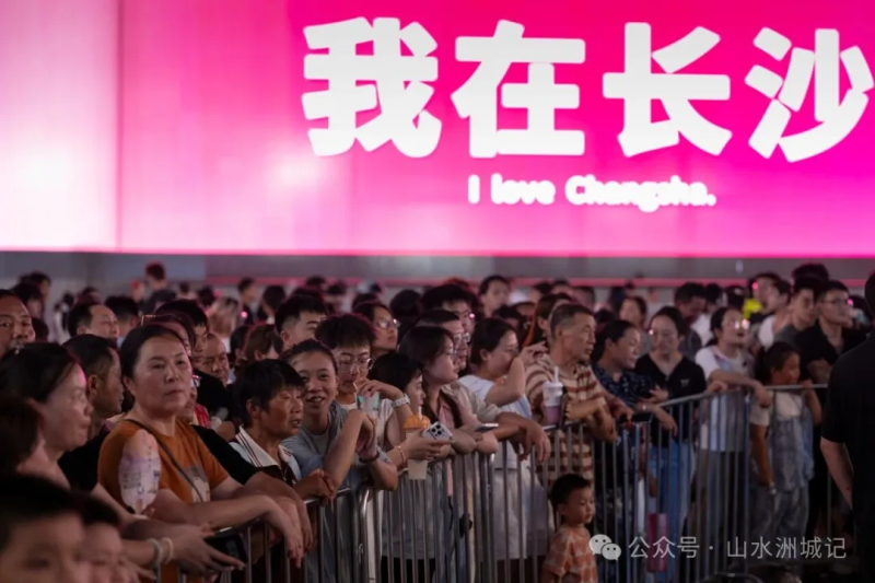路过的市民们在音乐会舞台前纷纷驻足，围了一圈又一圈。