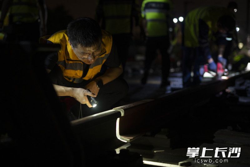 作业人员在对两条即将对接的钢轨进行仔细查看。