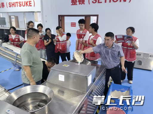 志愿服务队深入企业生产车间，近距离考察辣条生产设备的研发迭代、精工制造与市场应用全流程。
