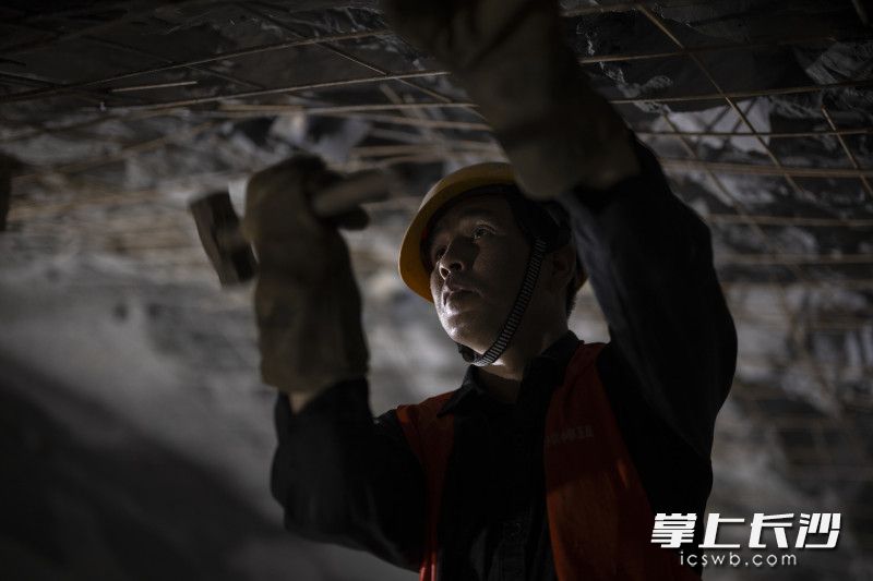 工人张应用锤子敲击铆钉进行加固。