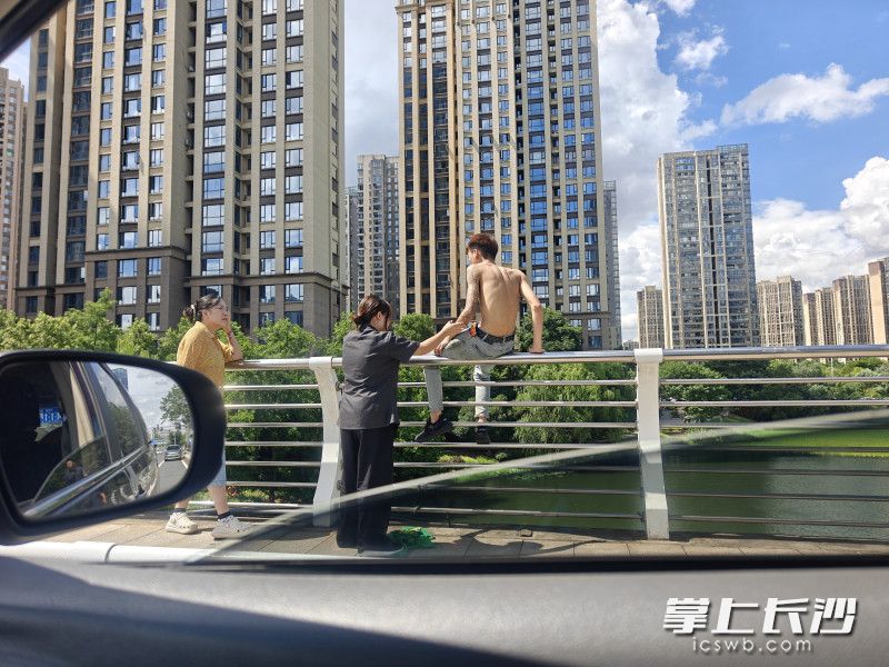 年轻男子坐在桥栏边缘，随时有坠落的危险。 均为长沙晚报通讯员 曾劲玉 供图