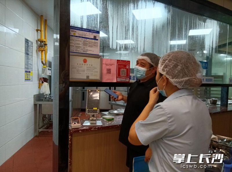 工作人员在企业食堂查看燃气安全管理制度等内容。