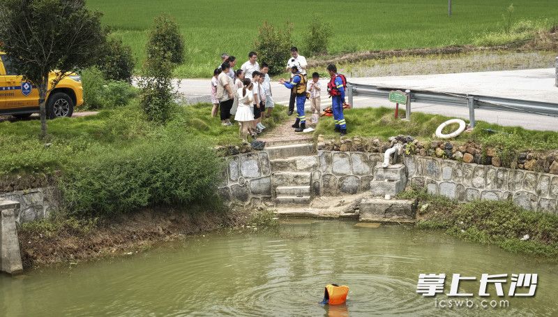 在水塘边，长沙县蓝天救援队队员对孩子们进行防溺水现场教学。