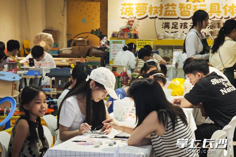 一商场的手作体验馆，家长和孩子们在制作手作。