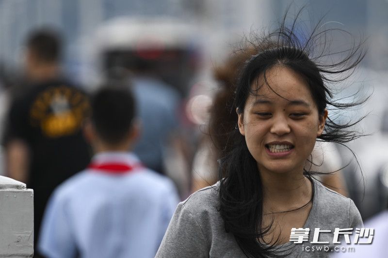 在橘子洲大桥，一位女士顶风出行。