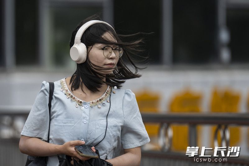 在车站路人行天桥，一位女士顶风出行。