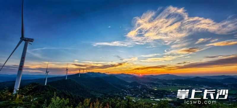 宁乡市道林镇神仙岭三一风电场，风电机组矗立山脊，叶片或静止或缓转，晚霞染红云层，远山村落一览无余。 周全 摄