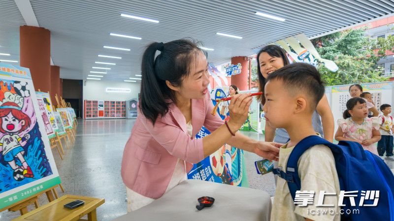 长塘里小学，校党总支书记肖陈慧为报道新生“点朱砂”。