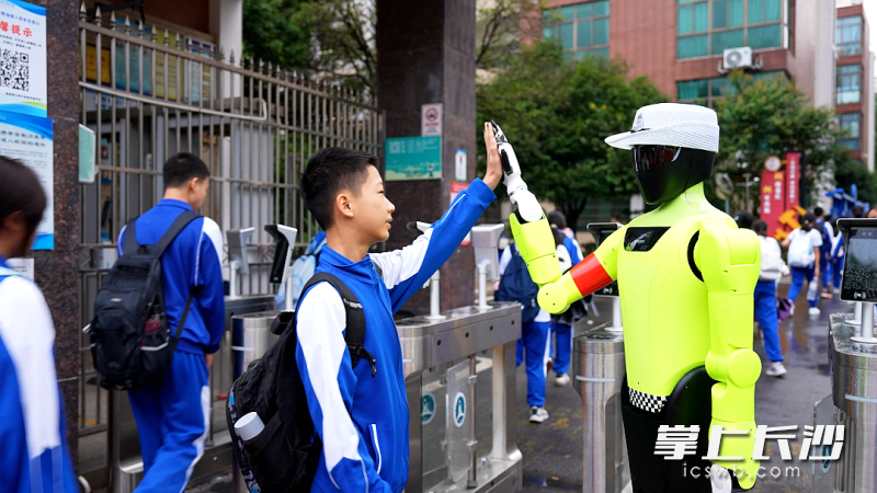 开学首日，机器人和入校学生击掌。 均为长沙晚报通讯员姚龙摄