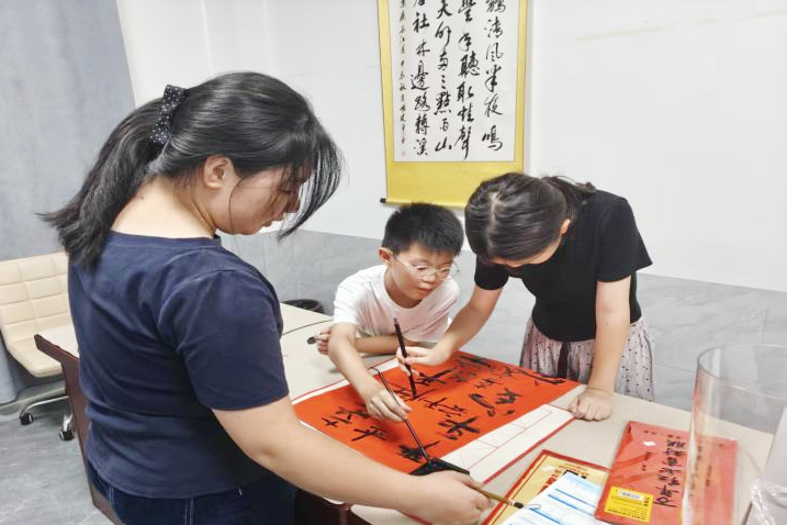 笔墨飘香的活动室里，志愿者俯身握笔指点，少年认真学习书法。