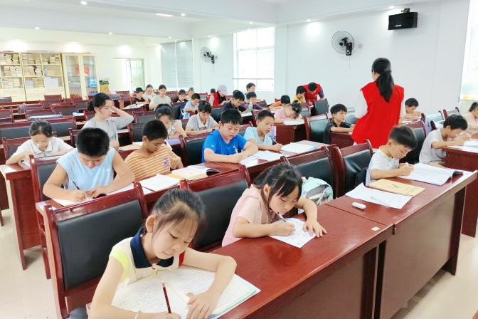 孩子们低头伏案、笔尖沙沙，志愿者不时俯身答疑，村部会议室成了安静又充实的“第二课堂”。