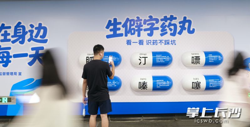 6颗巨型立体胶囊药丸吸睛，呈现“胍、缬、汀、嗪、嘌、噻”等常见生僻药名与科学用药提示。