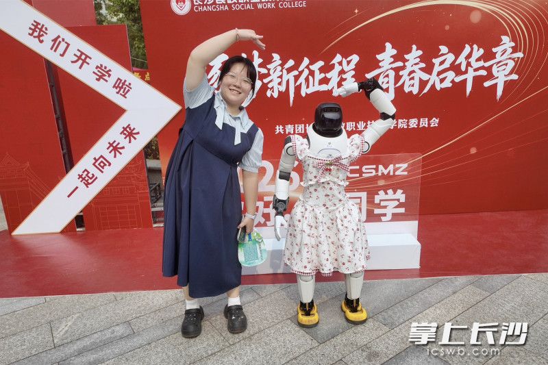 长沙民政学院大一新生和迎新机器人“民小达”互动合影。 均为长沙晚报全媒体记者张炎炎摄