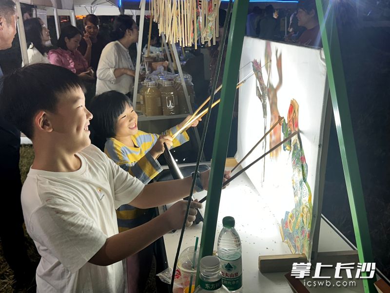 在摊位前，孩子们开心地操作皮影。湘江早报全媒体记者 黄荣佳 摄