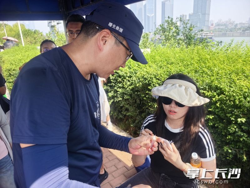 长沙曙光救援队员为游客发放防暑降温药品。