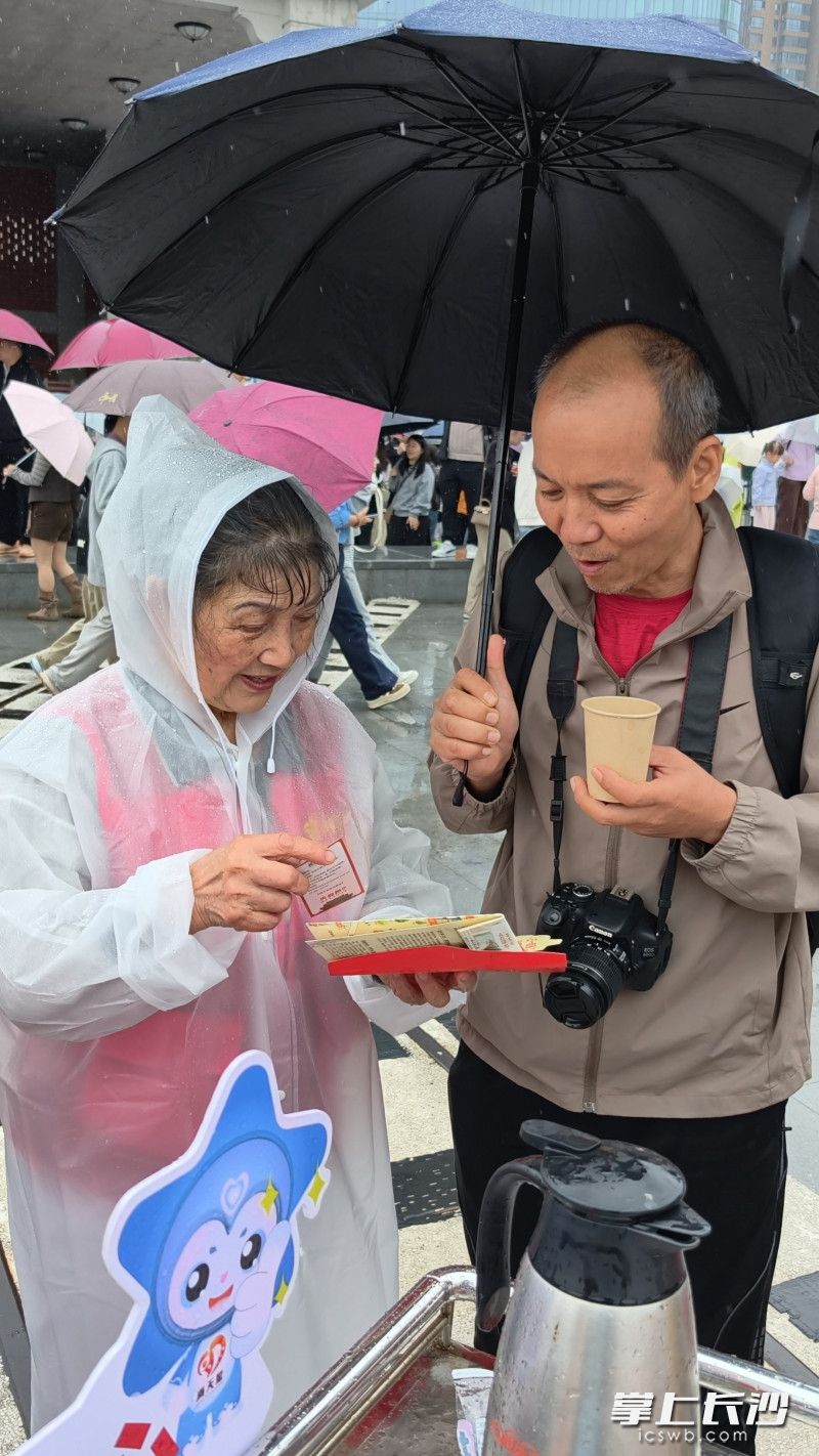 唐灼灼（左）冒雨为游客服务。