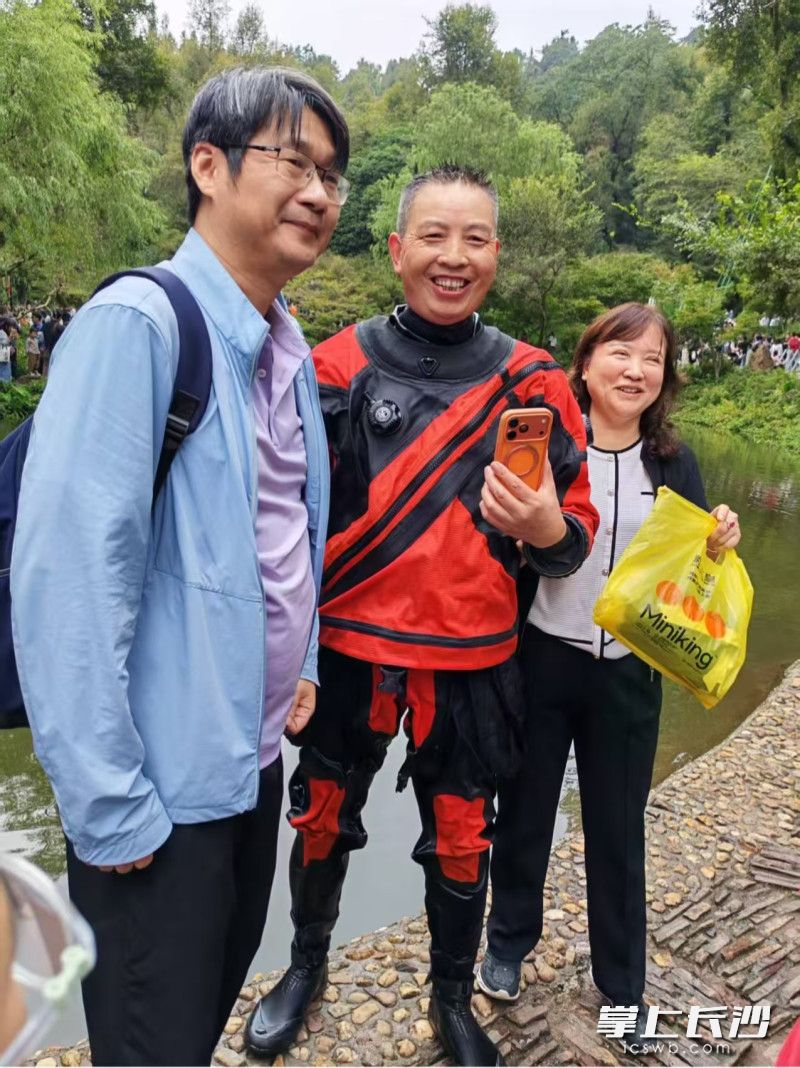 谭章（中）捞到手机后与游客合影。 受访者供图