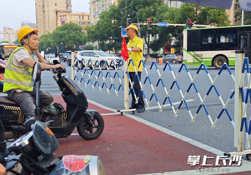 晚报大道车站北路口红灯亮起，伸缩护栏展开，将非机动车拦在等候区内。