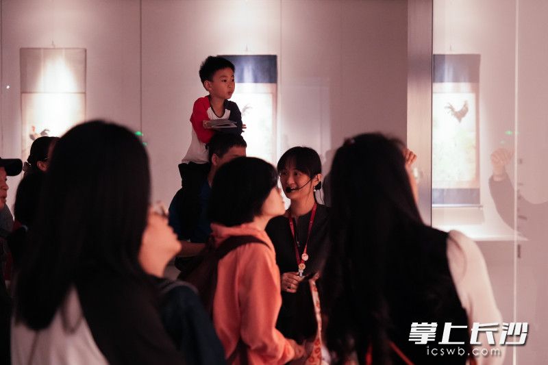 小朋友坐在父亲肩头,目光专注地欣赏展品。 小朋友坐在父亲肩头,目光专注地欣赏展品。